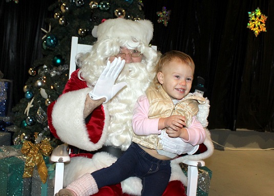 Santa Claus tells a little girl that he will bring her gifts.