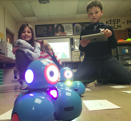 3rd grade student, Isabelle Tolbert, creating an algorithm for her robot to move towards the higher points on the board. The customized game board is projected onto the floor using a smart projector. As the robot moves and stops in the numbered squares the points disappear from the board. 